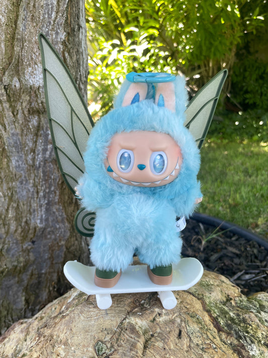 Blue fairy plush toy on a tree branch with greenery in the background